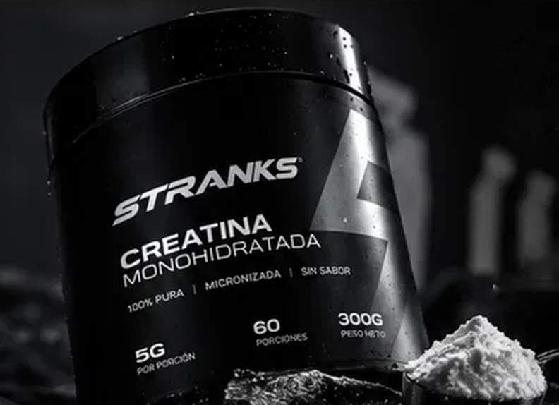 Pote de STRANKS Creatina inclinado junto a una medida con creatina en polvo